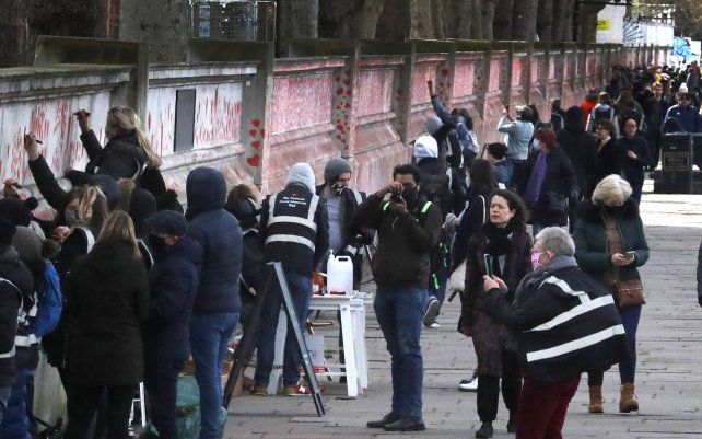 La gente pinta corazones rojos en el muro conmemorativo del COVID-19 en duelo por los fallecidos, frente a las Casas del Parlamento en el terraplén en Londres.