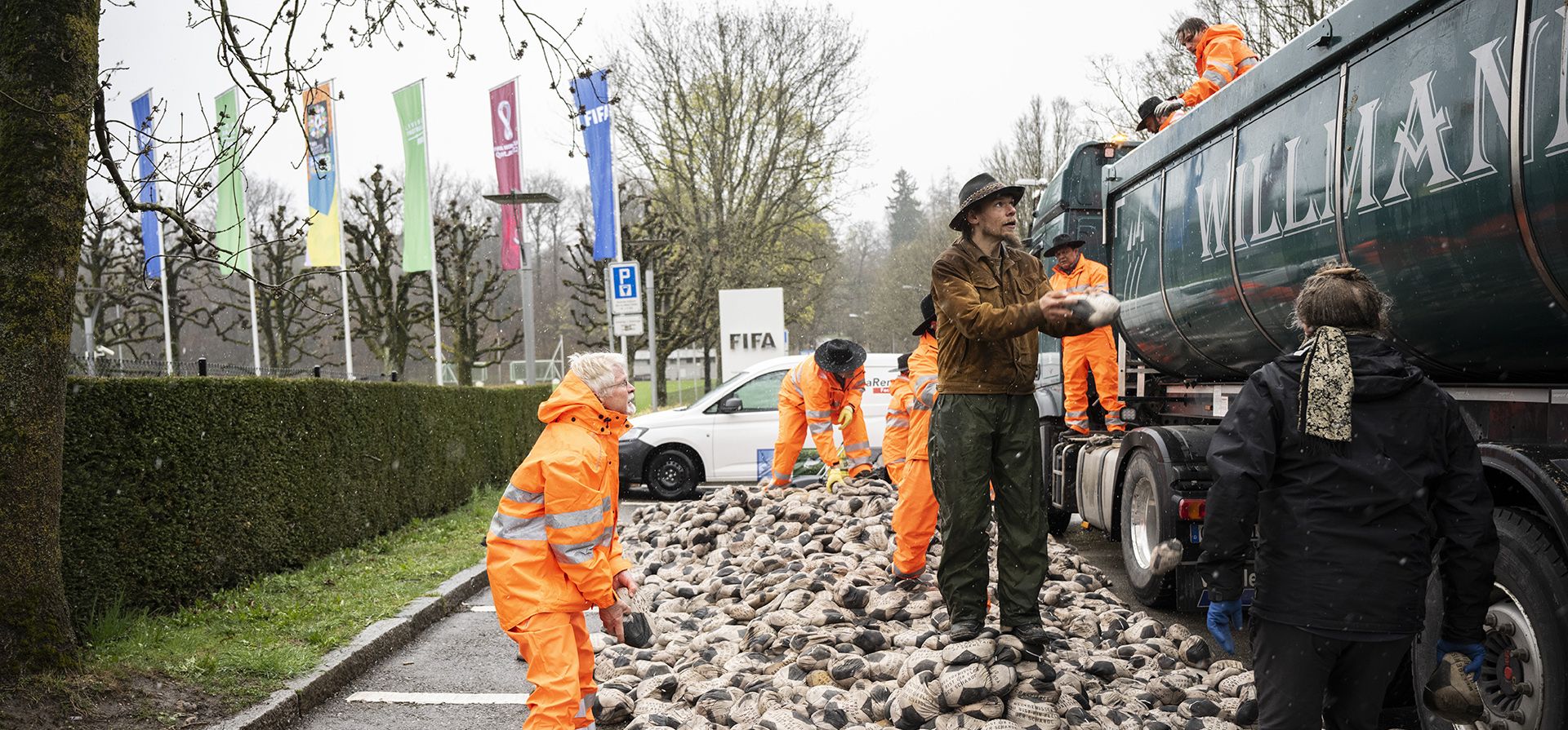 El artista alemán Volker-Johannes Trieb deja caer 6.500 balones de fútbol llenos de arena frente a la sede del organismo rector del fútbol mundial, la FIFA, en Zúrich, Suiza, el viernes 1 de abril de 2022. Está escrito