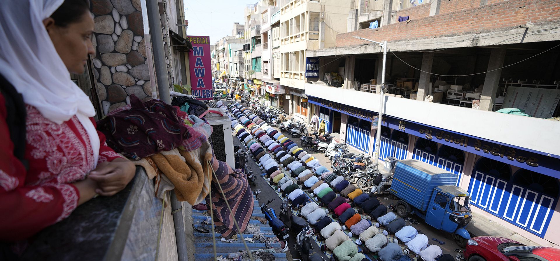Una mujer observa a los musulmanes rezar el último viernes del mes sagrado islámico del Ramadán en Ahmedabad, India, el viernes 29 de abril de 2022.