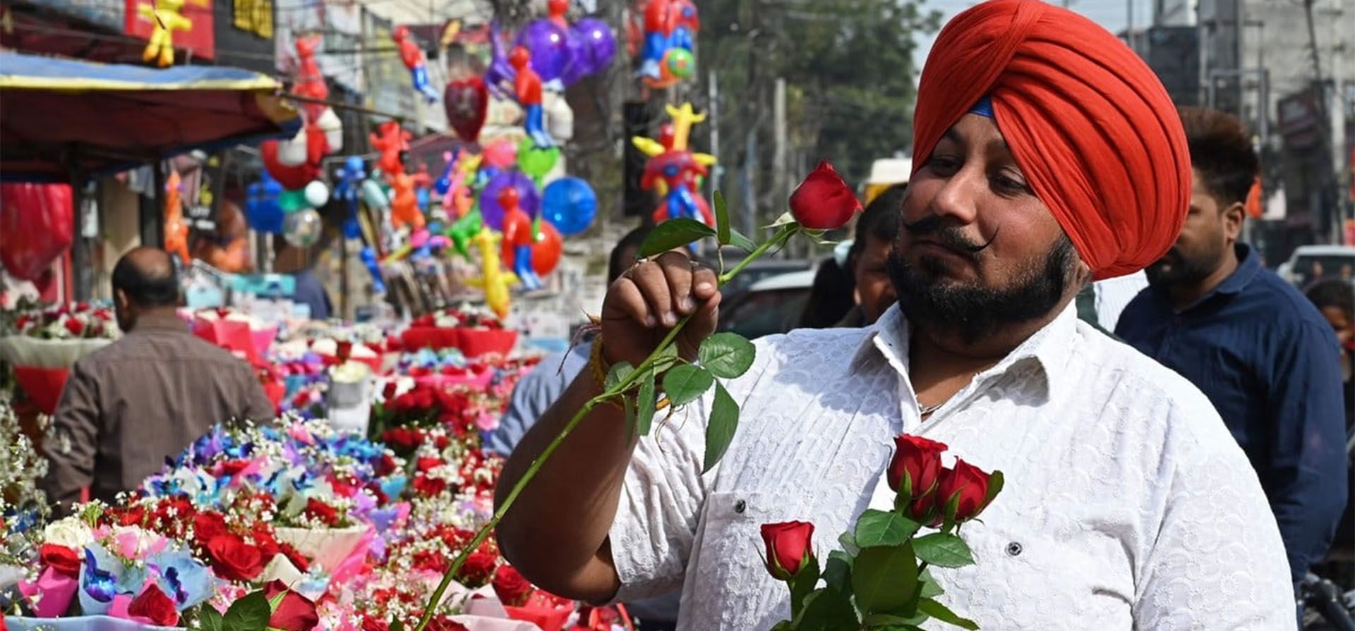Un hombre compra rosas en una tienda de una calle con motivo del Día de San Valentín en Amritsar, el 14 de febrero de 2023. (Fotografía de Narinder NANU / AFP)    