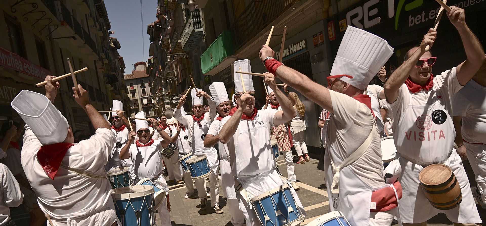 La gente toca tambores vestidos con los colores de San Fermín en las Fiestas de San Fermín en Pamplona, norte de España, el viernes 8 de julio de 2022. Turistas de todo el mundo acuden a la ciudad cada año durante nueve días de fiesta ininterrumpida en el famoso festival de corridas de toros de Pamplona, que estuvo suspendido durante los últimos dos años debido a la pandemia de coronavirus.