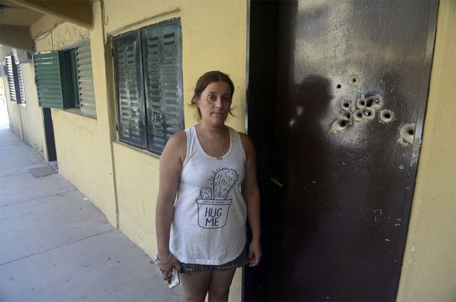 Carla junto a las marcas de balazos en la puerta de su casa.