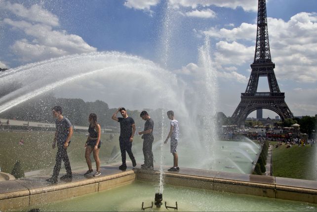 Al rojo vivo. Jóvenes franceses buscan algo de alivio en las fuentes de París junto a la torre Eiffel.