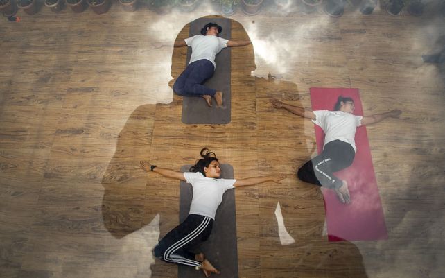 Mujeres indias realizan yoga para conmemorar el Día Internacional del Yoga en la parte superior de un edificio en Gauhati