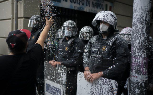 Agentes de la policía antidisturbios cubiertos por pintura arrojada por los manifestantes, montan guardia, mientras los activistas intentan detener el desalojo de Axel Altadill, de 28 años, de su apartamento en Barcelona, España. Altadill fue acusado de ocupar el apartamento desde enero de 2019.