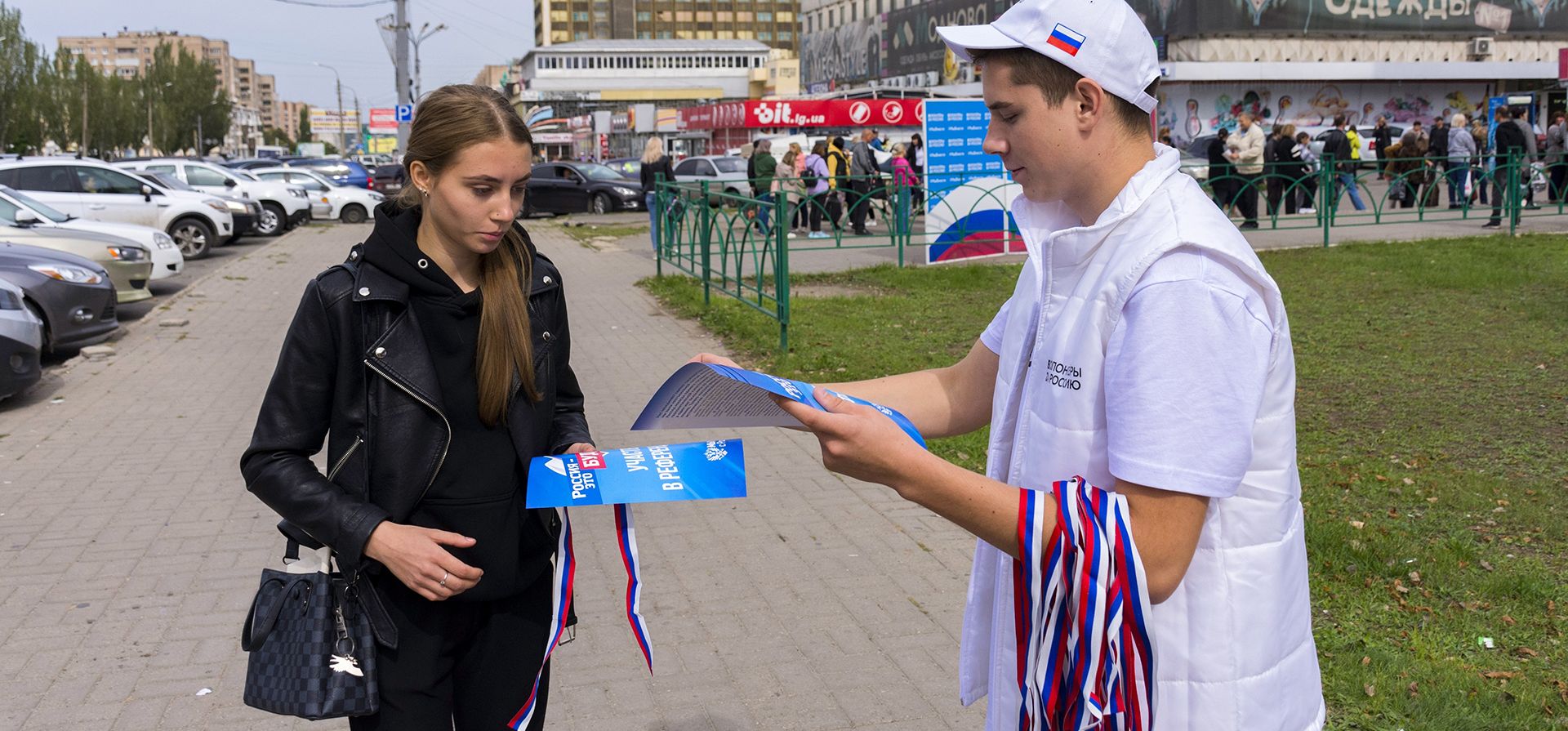 Un voluntario de la comisión electoral regional de Lugansk, distribuye cintas con los colores de la bandera nacional rusa y carteles que dicen "Rusia es el futuro, ¡participe en el referéndum!" a los ciudadanos locales antes de un referéndum en Luhansk, República Popular de Lugansk controlada por separatistas respaldados por Rusia, en el este de Ucrania, el jueves 22 de septiembre de 2022.
