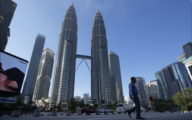 Un transeúnte camina por una calle vacía frente a las Torres Gemelas durante el primer día de la Orden de Control de Movimiento Total (MCO) en Kuala Lumpur, Malasia.