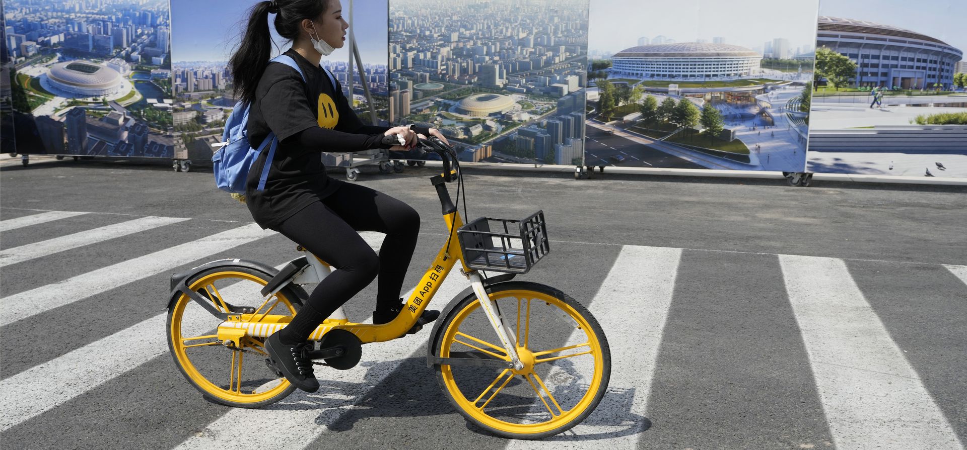 Una mujer pasa junto a obras de arte del recientemente renovado Estadio de los Trabajadores en Beijing, el miércoles 10 de mayo de 2023. (Foto AP/Ng Han Guan)