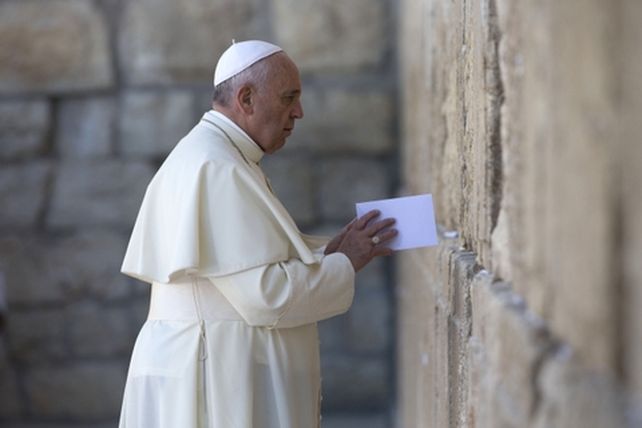 Francisco coloca un sobre entre las piedras del Muro de los Lamentos