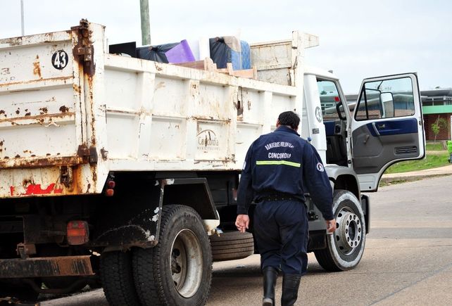 Un bombero salva del agua colchones que son trasladados en un camión de la Municipalidad de Concordia. &nbsp; 
