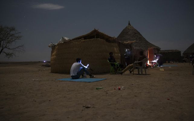 Refugiados de Tigray que huyeron del conflicto de Etiopía intentan encontrar una señal de red para sus teléfonos móviles en Hamdayet