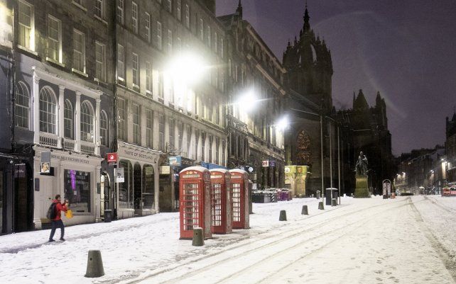 Un hombre toma una foto de la nieve a lo largo de la Royal Mile en Edimburgo. El centro y sureste de Escocia se encuentra amenazado por la tormenta Christoph con pronóstico climáticos desafiantes.