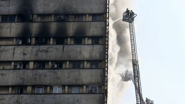 Bomberos trabajan en extinción de las llamas en el edificio. Poco después colapsaría.