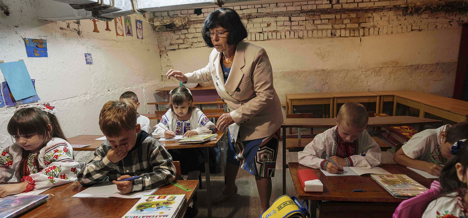 Alumnos escuchan a su profesor durante una clase en el sótano de un edificio municipal durante el primer día de clases en Bobryk, región de Sumy, Ucrania, el lunes 1 de septiembre de 2025. La escuela de Bobryk se vio obligada a trasladarse al sótano debido a las constantes alarmas. (Foto AP/Evgeniy Maloletka) Alumnos escuchan a su profesor durante una clase en el sótano de un edificio municipal durante el primer día de clases en Bobryk, región de Sumy, Ucrania, el lunes 1 de septiembre de 2025. La escuela de Bobryk se vio obligada a trasladarse al sótano debido a las constantes alarmas. (Foto AP/Evgeniy Maloletka)