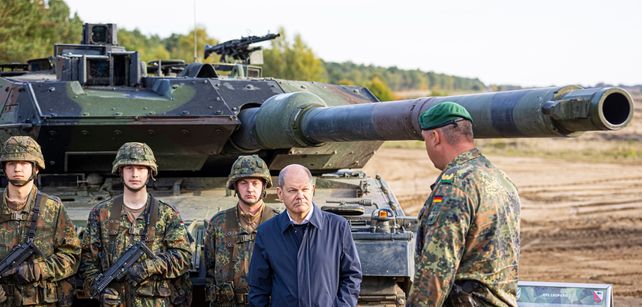El canciller alemán Olaf Scholz parado junto a soldados delante de un tanque Leopard 2