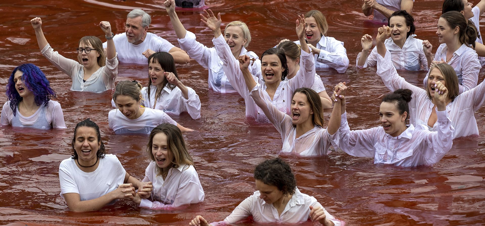 La gente se baña en un estanque, de color rojo simulando sangre, durante una actuación de protesta contra la invasión rusa de Ucrania frente a la embajada rusa en Vilnius, Lituania, el jueves 7 de abril de 2022. Las autoridades ucranianas dijeron que se encontraron los cuerpos de 410 civiles en ciudades del área de Kiev que recientemente fueron recuperadas de las fuerzas rusas.