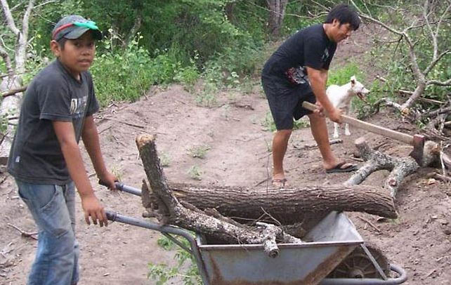 La imagen muestra a Iber Flores junto a su tío Oscar Talero en los trabajos de la comunidad qom.