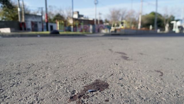 Rastros de sangre en el lugar donde una mujer sufrió heridas de bala, frente a una plaza en zona sur