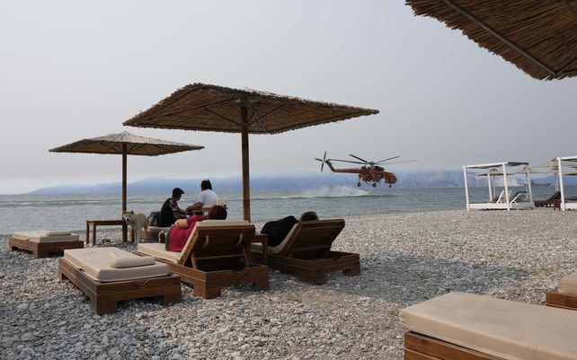 Un helicóptero se carga de agua en cercanías de la playa