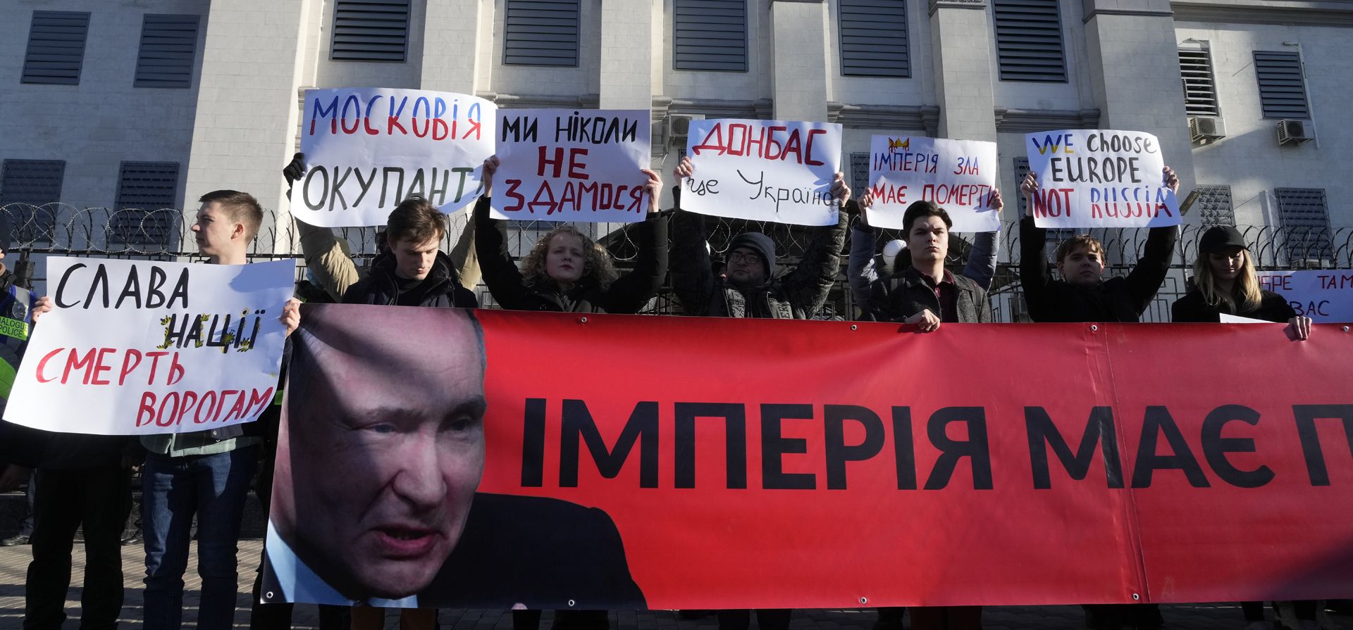 Manifestantes sostienen carteles que dicen: "¡Nunca nos rendiremos!, Donbass es Ucrania, el imperio debe morir" y una pancarta que dice "El imperio debe morir" frente a la embajada rusa en Kiev, Ucrania, el martes 22 de febrero de 2022.