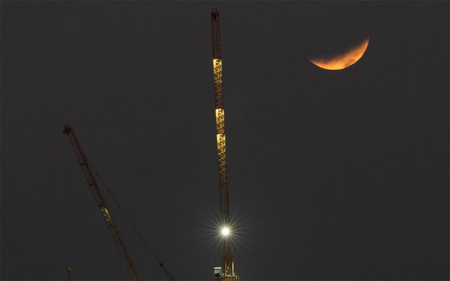 Un eclipse parcial de luna se ve detrás de una grúa en Manila