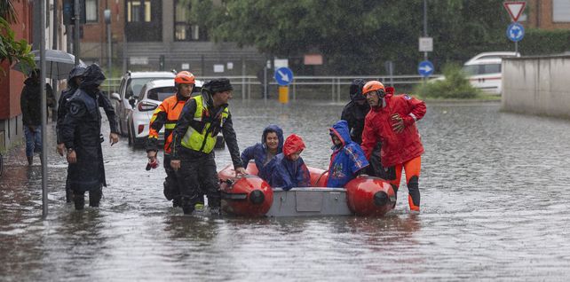 Los bomberos utilizan un bote auxiliar para evacuar a una mujer y dos niños después de que parte de la ciudad se inundara tras lluvias persistentes