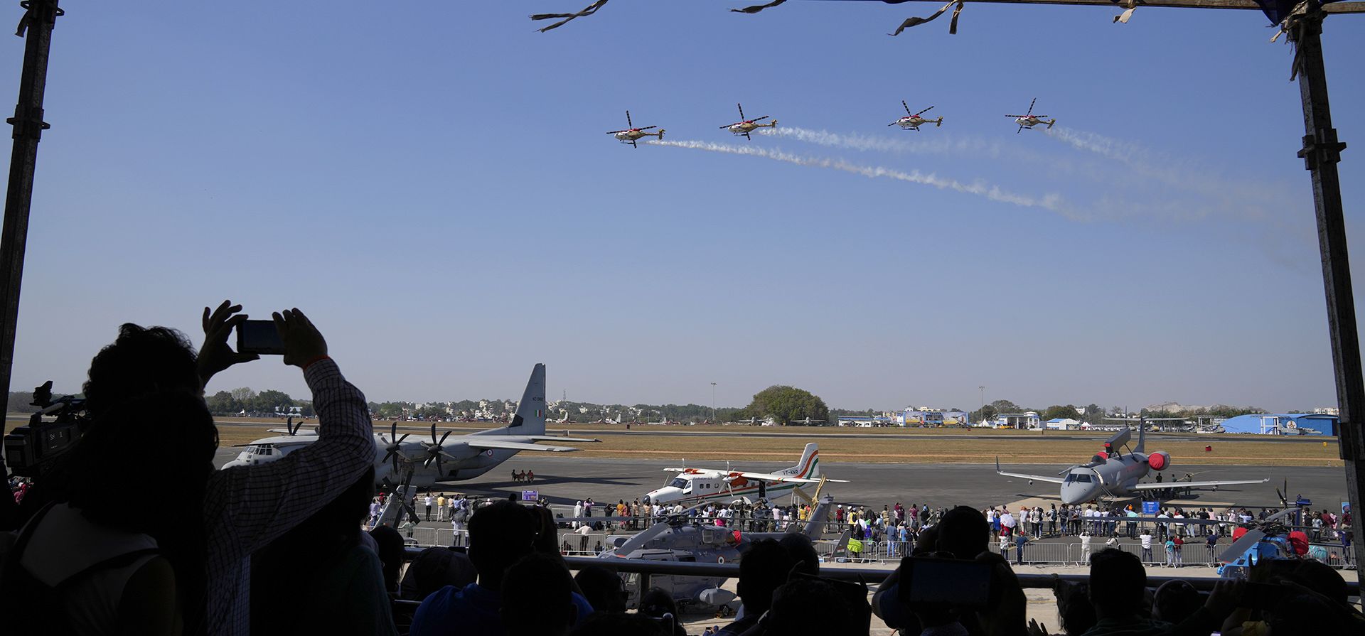 El público observa al equipo acrobático Sarang de la Fuerza Aérea India volar en formación sobre un área de visualización estática en el cuarto día de Aero India 2023 en la base aérea de Yelahanka en Bengaluru, India, el jueves 16 de febrero de 2023. (Foto AP/Aijaz Rahi)