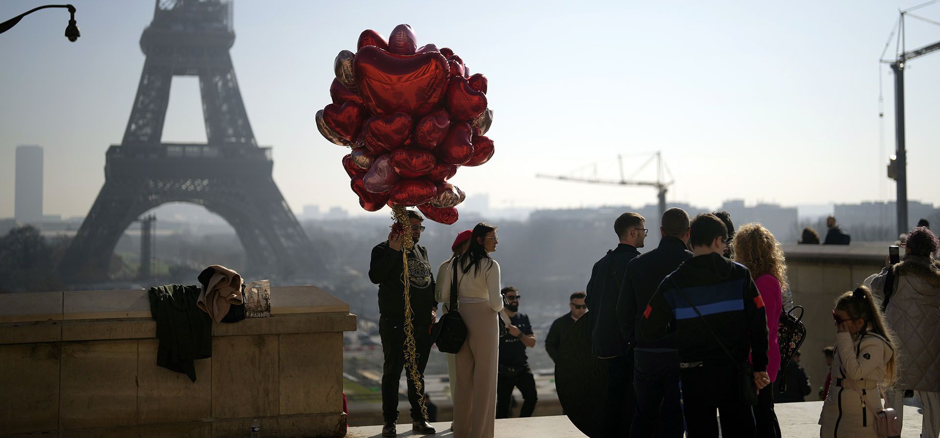 Una pareja sostiene globos rojos en forma de corazón durante el día de San Valentín, frente a la Torre Eiffel, en París, el martes 14 de febrero de 2015. (Foto AP/Thibault Camus)