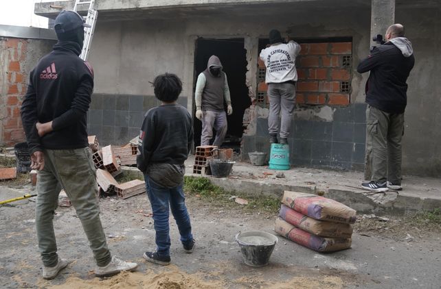 Vecinos miran cómo inhabilitan la casa en la que se planearon los crímenes de trabajadores en marzo.&nbsp;
