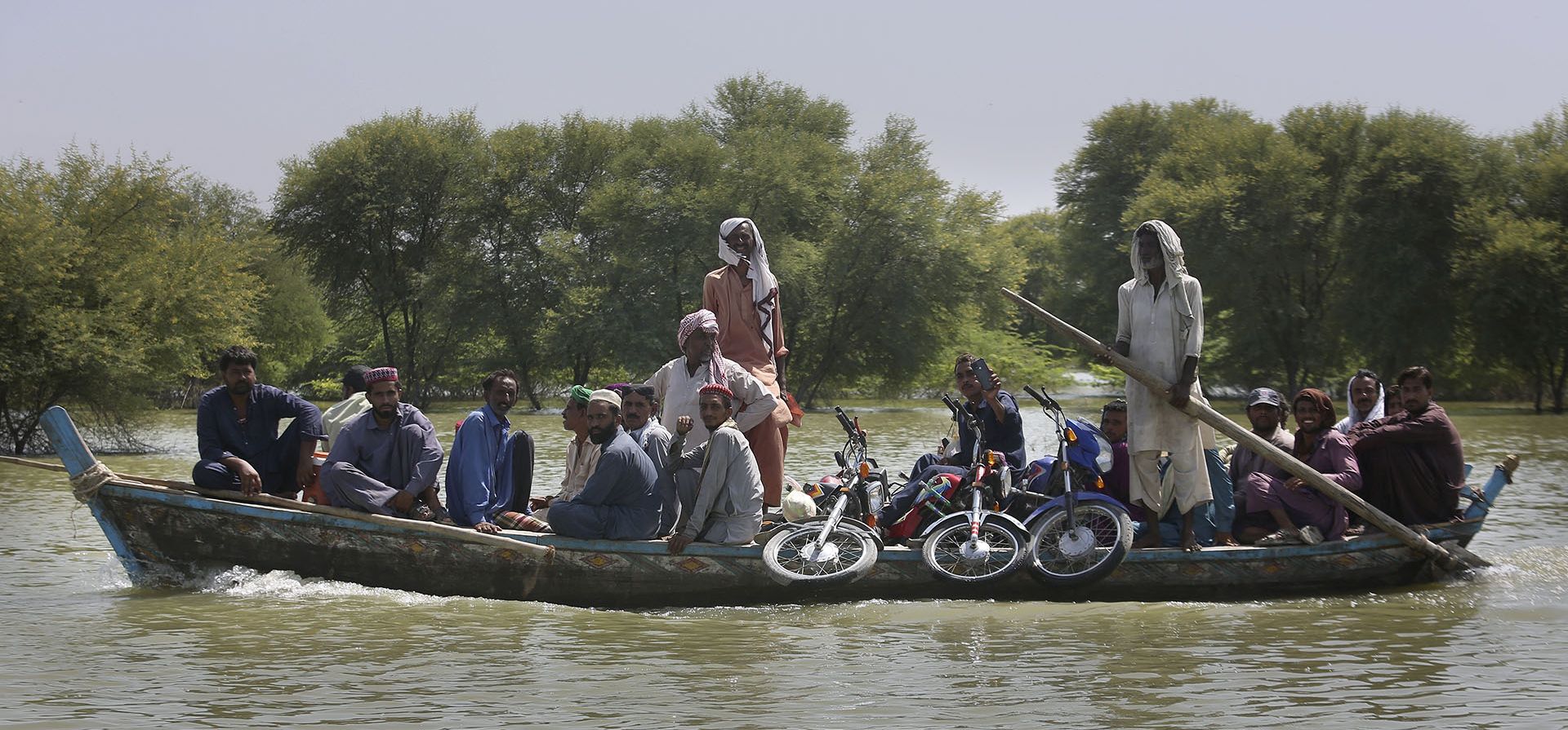 Un grupo de aldeanos con sus pertenencias cruzan un área inundada en un bote, en Dadu, un distrito de la provincia sureña de Sindh, Pakistán. La devastación causada por las inundaciones en Pakistán este verano ha intensificado el debate sobre una cuestión de justicia climática: ¿Los países ricos cuyas emisiones son la principal causa del cambio climático deben una compensación a los países pobres afectados por desastres provocados por el cambio climático?