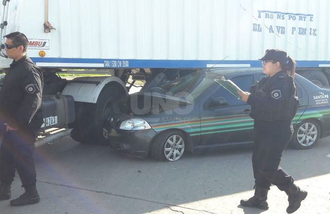 El auto oficial quedó bajo una camión.