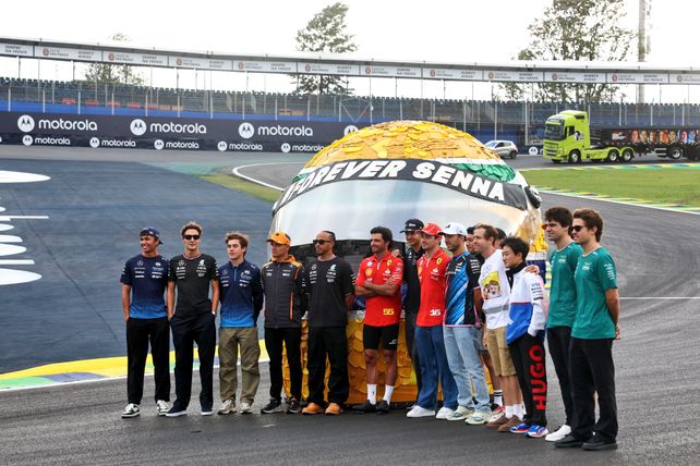 Todos los pilotos formados frente al casco de Senna en la recta principal.