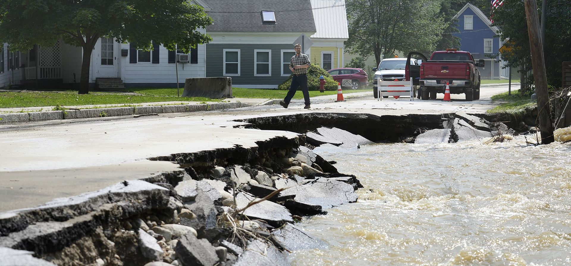 Un transeúnte camina cerca de una calle dañada por las aguas de la inundación, en Ludlow, Vt. Una tormenta que arrojó dos meses de lluvia en dos días causó erosión a lo largo de muchas carreteras en el estado. (Foto AP/Steven Senne) Un transeúnte camina cerca de una calle dañada por las aguas de la inundación, en Ludlow, Vt. Una tormenta que arrojó dos meses de lluvia en dos días causó erosión a lo largo de muchas carreteras en el estado. (Foto AP/Steven Senne)
