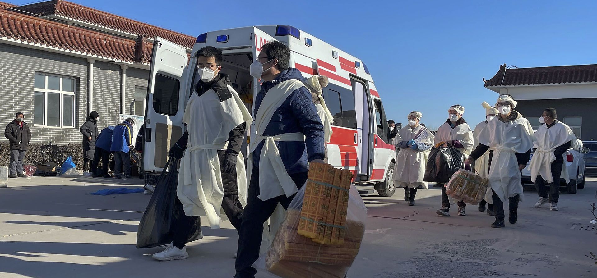 Miembros de una familia llevan bolsas de ofrendas de papel para su pariente fallecido en la funeraria Gaobeidian, en la provincia de Hebei, en el norte de China, el jueves 22 de diciembre de 2022. China solo cuenta las muertes por neumonía o insuficiencia respiratoria en su cifra oficial de muertes por COVID-19, un informe de salud chino. (Foto AP)