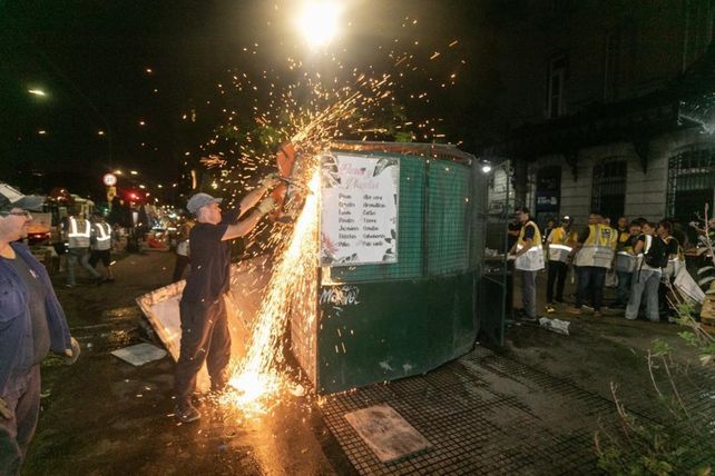 Un agente municipal se vale de una gran amoladora para desarmar un puesto de flores.