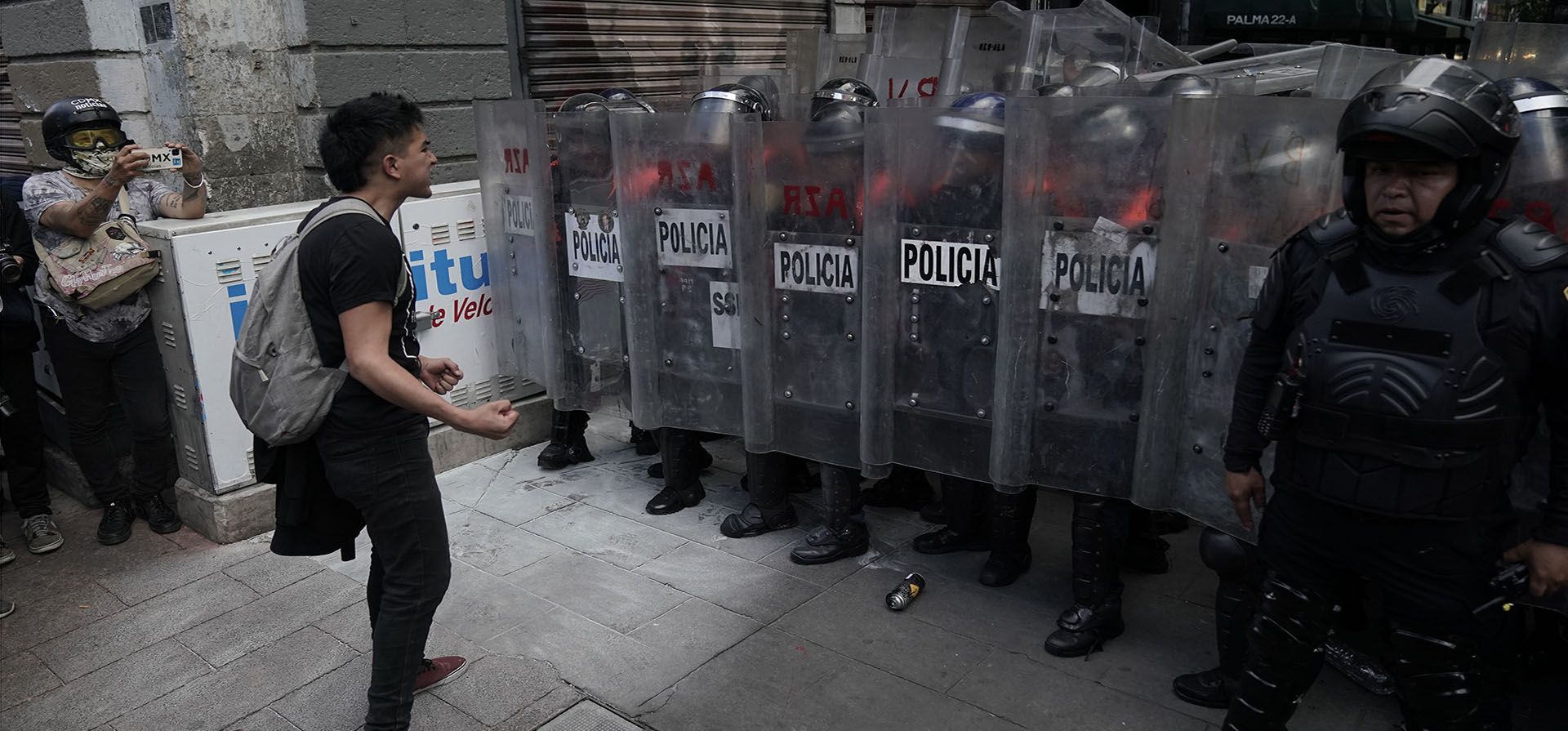 Un joven se enfrenta a una falange de policías antidisturbios durante una marcha por los 43 estudiantes universitarios de Ayotzinapa desaparecidos en la Ciudad de México, el martes 27 de septiembre de 2022, el día del aniversario de la desaparición de los estudiantes en Iguala, estado de Guerrero. Tres miembros de las fuerzas armadas y un exfiscal general federal fueron arrestados recientemente por el caso.