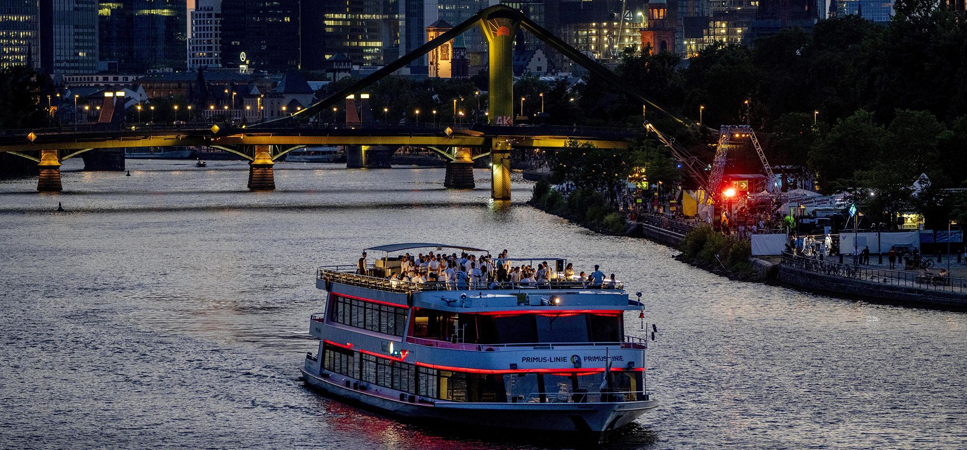 Un barco de fiesta navega por el río Meno con los edificios del distrito bancario al fondo en la ciudad de Frankfurt, Alemania.