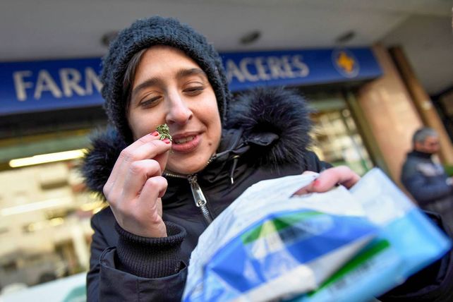 Una joven muestra y a la vez percibe los gramos de cannabis a la salida de una farmacia de Montevideo.