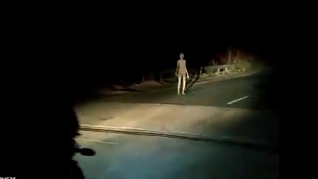 El presunto extraterrestre camina por una ruta mientras es observado y grabado por automovilistas y motociclistas.