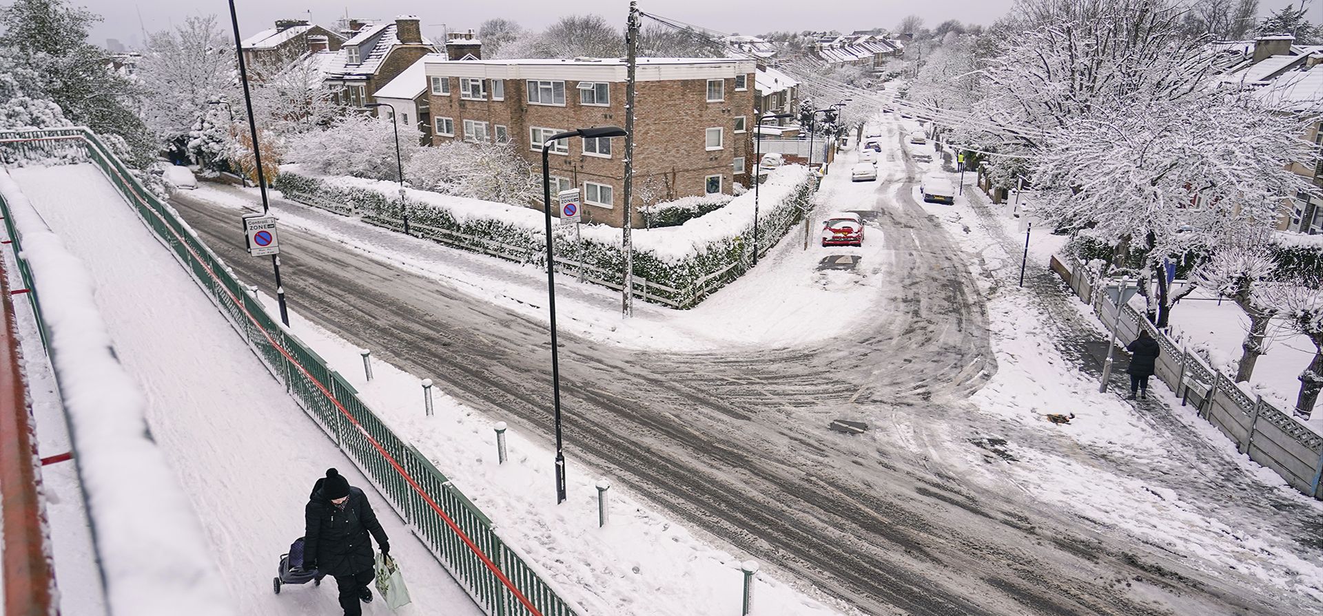 Una mujer tira de un carrito de compras en una zona residencial cubierta de nieve en Leytonstone, en Londres, el lunes 12 de diciembre de 2022. La nieve y el hielo han barrido partes del Reino Unido, con condiciones invernales frías que continuarán durante días. (Foto AP/Alberto Pezzali)