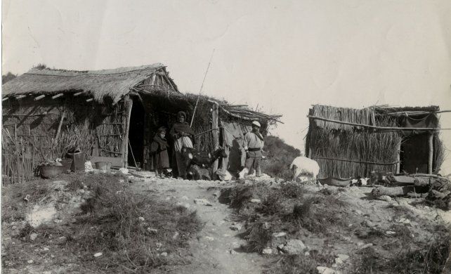 Vivienda precaria de adobe y paja en el monte. Junto al hachero, su mujer e hija y animales de corral. Archivo General de la Nación