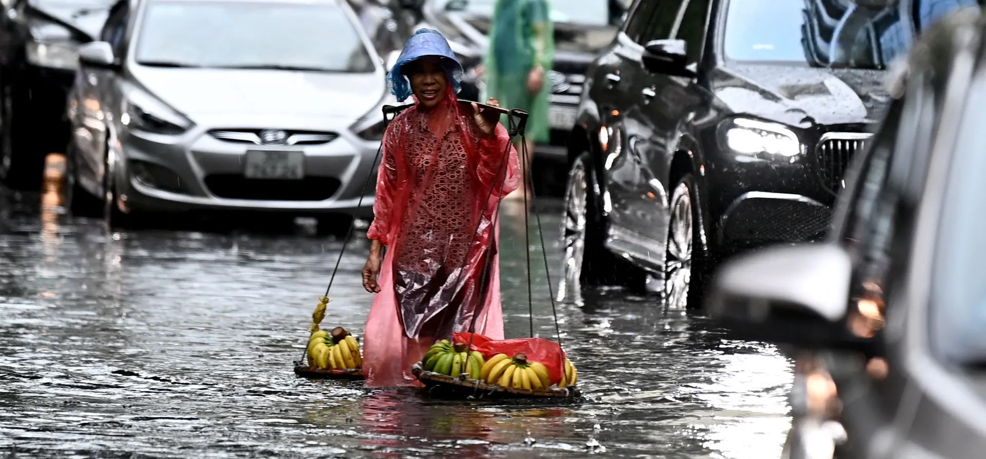 Una mujer que vende plátanos camina por una calle inundada, Hanoi, Vietnam. Fotografía: Nhac Nguyen/AFP/Getty Images Una mujer que vende plátanos camina por una calle inundada, Hanoi, Vietnam. Fotografía: Nhac Nguyen/AFP/Getty Images