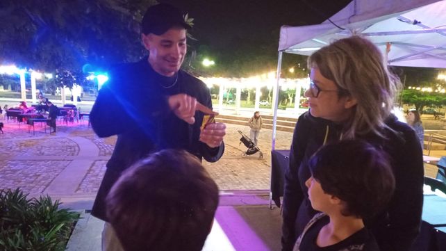 El mago Mistik ocupado en enseñarle a chicos y grandes los trucos que tiene a la venta en su pequeño stand.