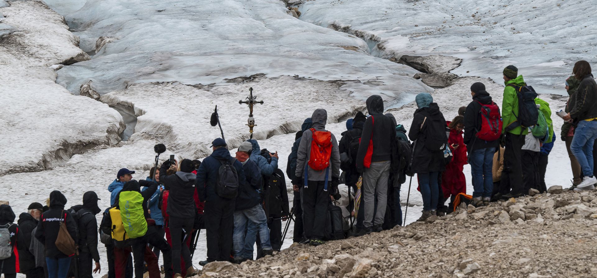 Un grupo de personas liderados por el sacerdote católico Florian Hammerl y el sacerdote protestante Uli Wilhelm se detienen a bendecir lo que queda del glaciar Zugspitz en Garmisch-Partenkirchen, Alemania, el martes 25 de julio de 2023. (Peter Kneffela/dpa vía AP)