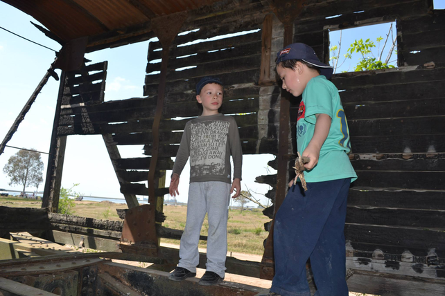 Un viejo vagón de madera abandonado es el lugar escogido por los niños para jugar. De fondo se puede contemplar el espejo de agua.