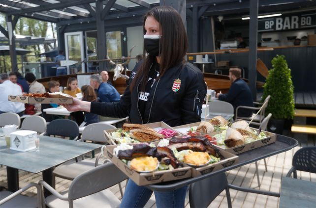 Una camarera sirve comida en la terraza exterior de un bar en Budapest