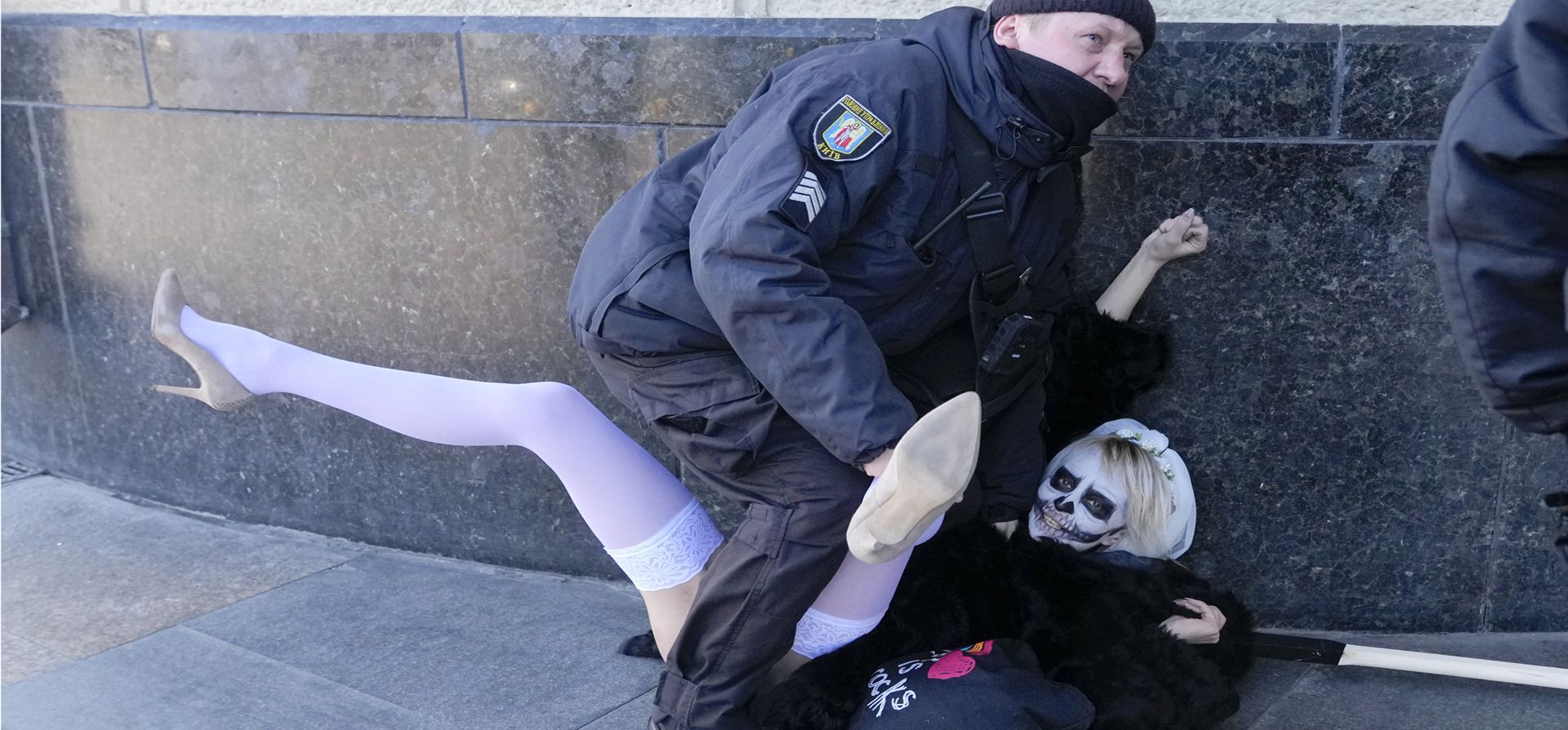 Un oficial de policía detiene a una activista del movimiento de mujeres FEMEN durante su actuación frente a la estación central de trenes en Kiev, Ucrania, el martes 20 de febrero de 2022.