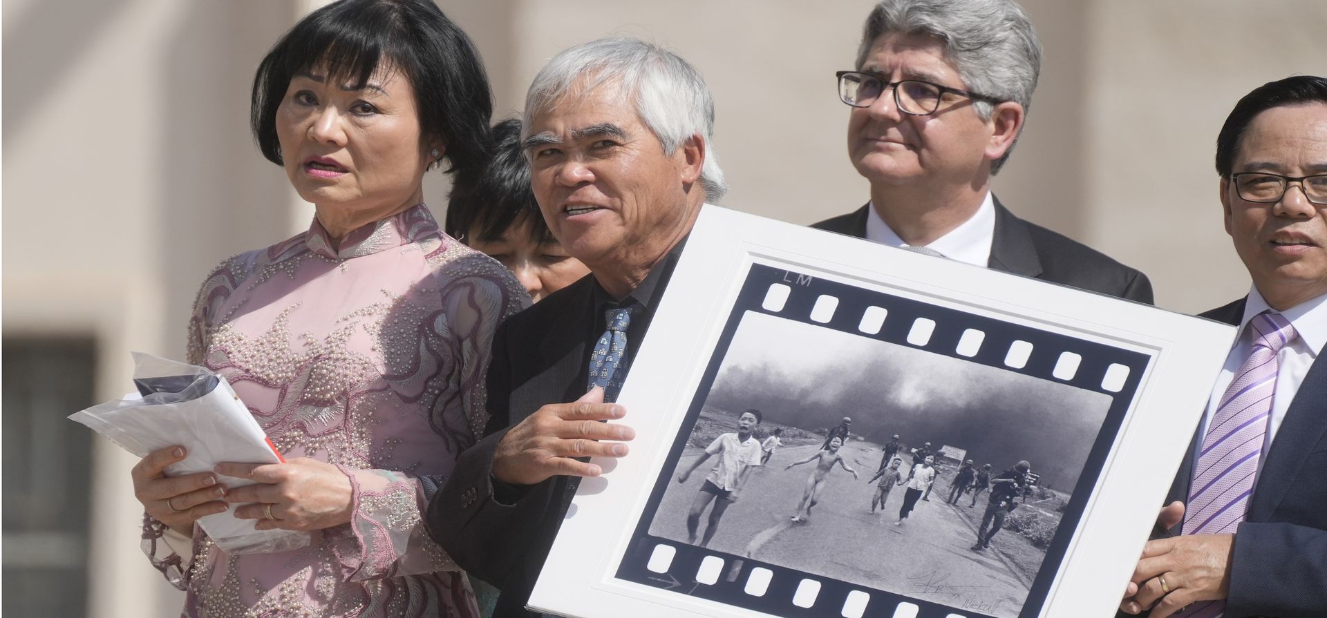 El fotógrafo ganador del Premio Pulitzer Nick Ut, centro, flanqueado por Kim Phuc, sostiene la