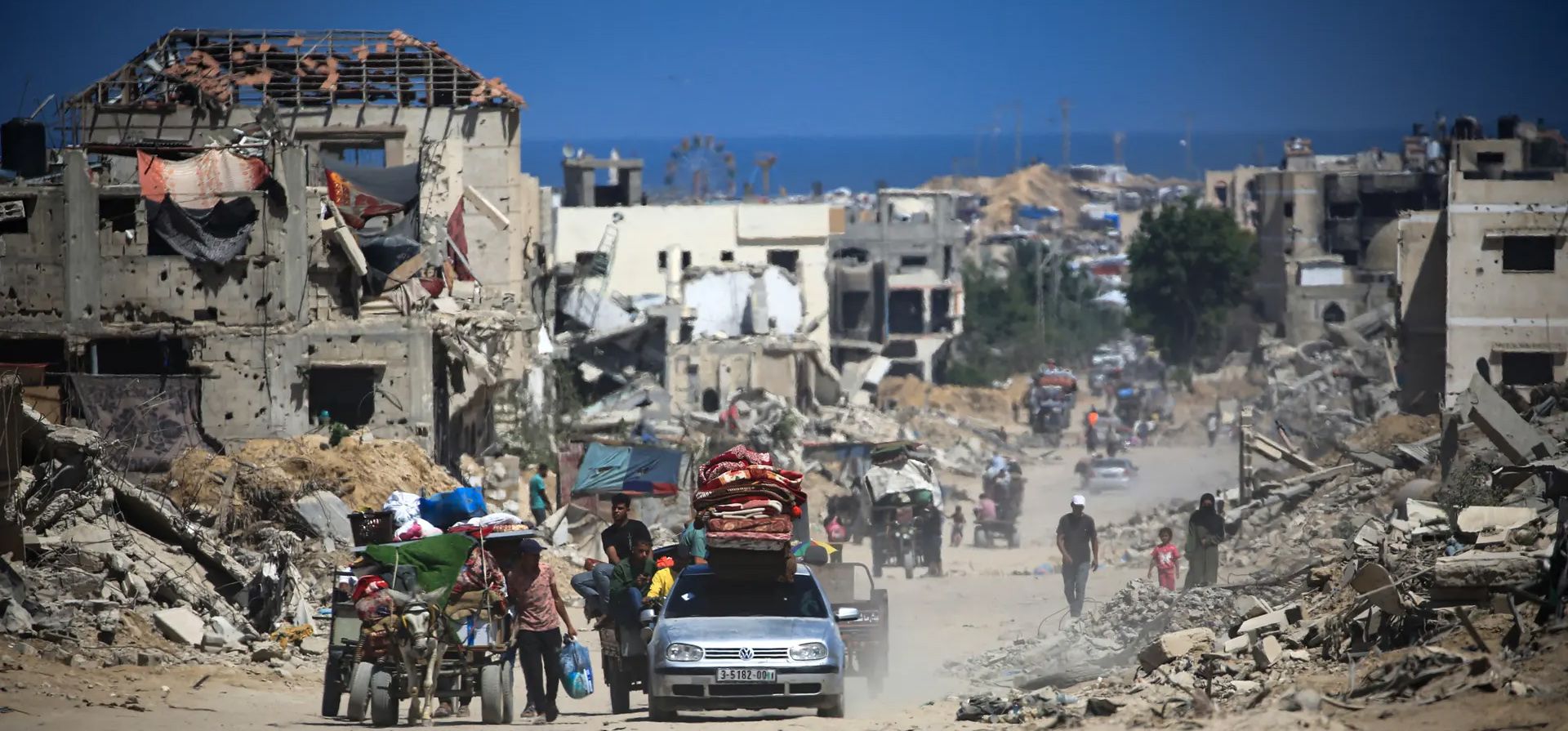 Los palestinos caminan y conducen junto a los edificios destruidos durante los bombardeos israelíes en el sur de la Franja de Gaza en medio del conflicto entre Israel y el grupo militante palestino Hamas, Khan Younis, Gaza. Fotografía: Eyad Baba/AFP/Getty Images Los palestinos caminan y conducen junto a los edificios destruidos durante los bombardeos israelíes en el sur de la Franja de Gaza en medio del conflicto entre Israel y el grupo militante palestino Hamas, Khan Younis, Gaza. Fotografía: Eyad Baba/AFP/Getty Images