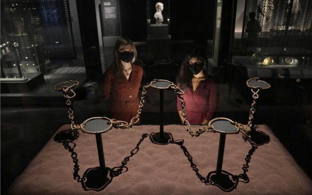 Empleadas del museo posan para los fotógrafos junto a las cadenas de bandas que datan del 100 a. C. al 78 d. C. que tenían a personas esclavizadas o prisioneros y fueron encontrados en un lago en la isla de Mona (hoy llamada Anglesey) en el noroeste de Gales.